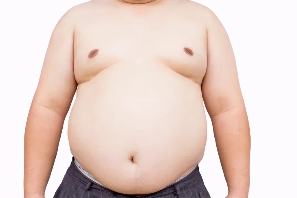 Front view of a man's bare torso and abdomen with his arms resting at his sides against a white background.